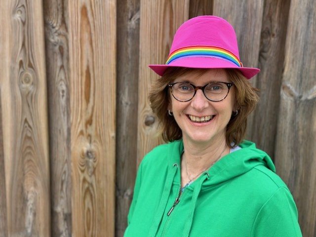 Lachyoga, lachwandelingen en coaching in Den Bosch? Celest van der Geld helpt Celest, lachend met een vrolijke hoed met regenboog en roze op